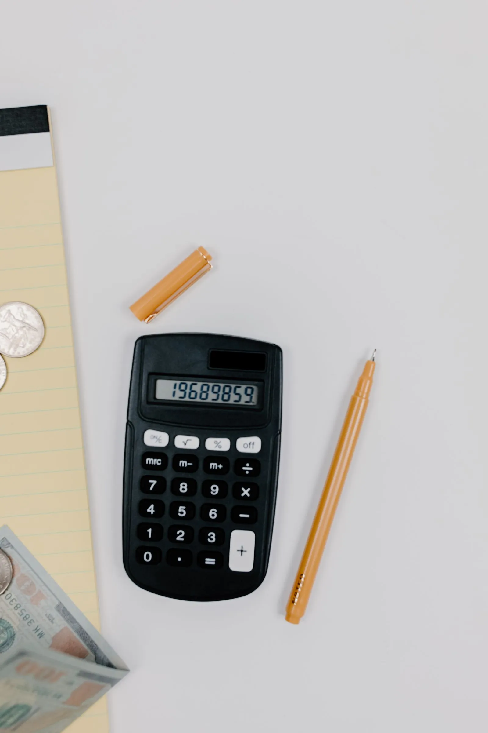 A calculator, pencil and notepad on a desk
