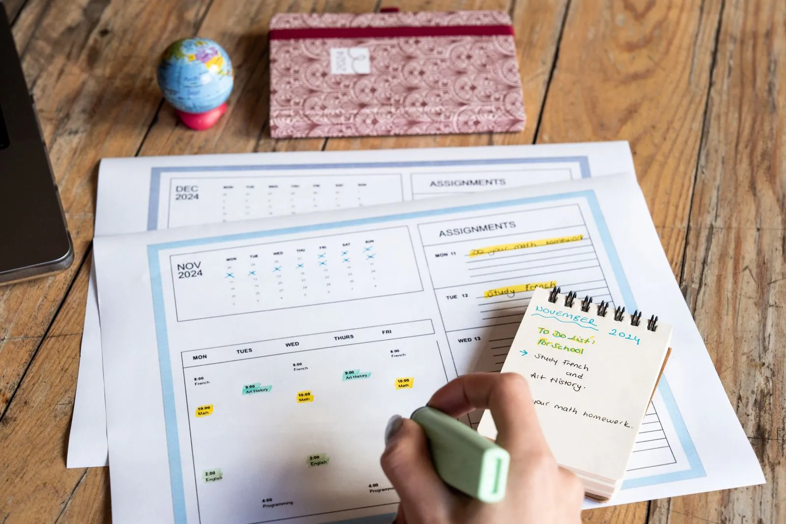 A hand marking tasks on a printed monthly calendar