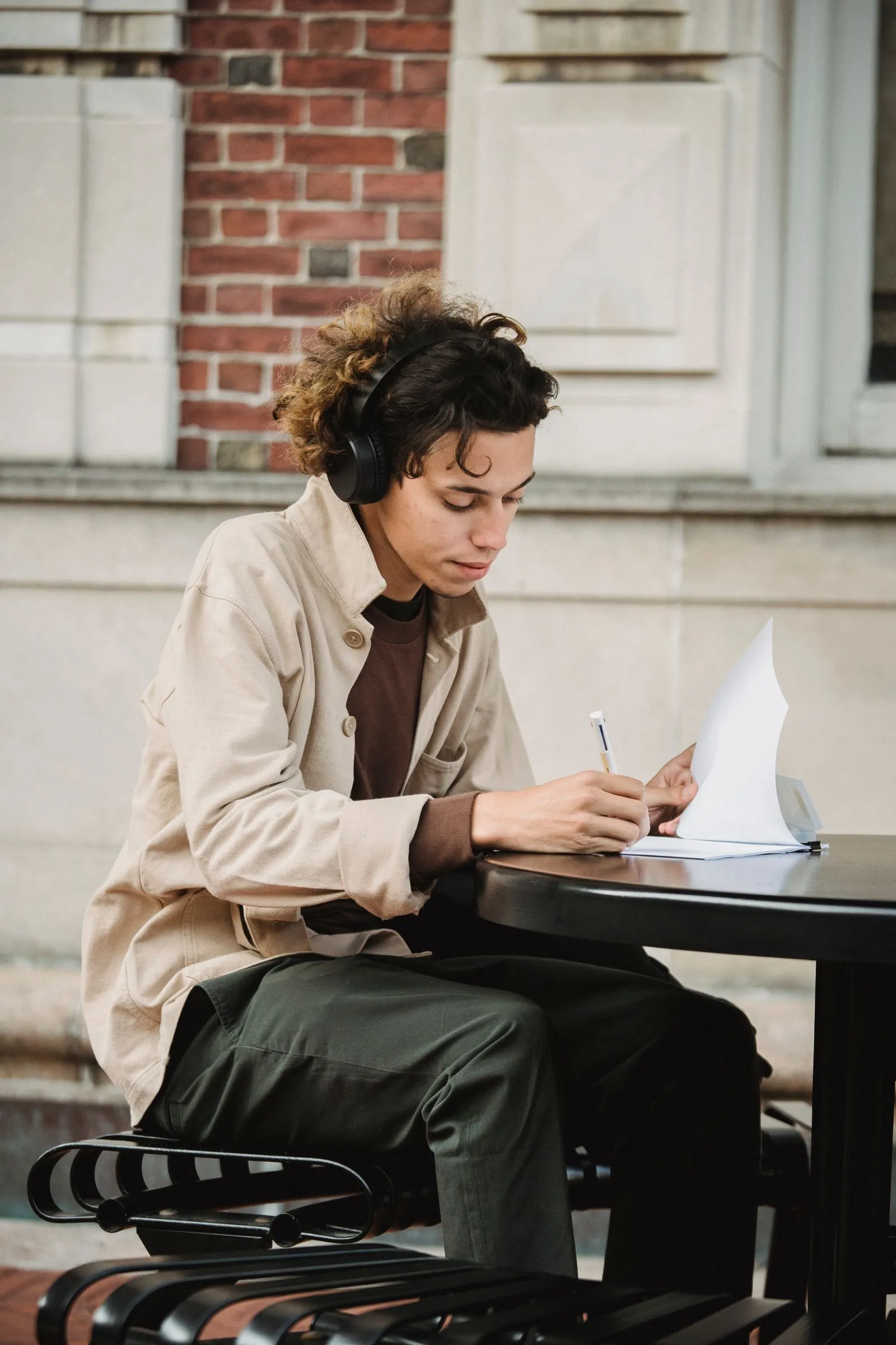 A student wearing headphones writes answers on a test sheet