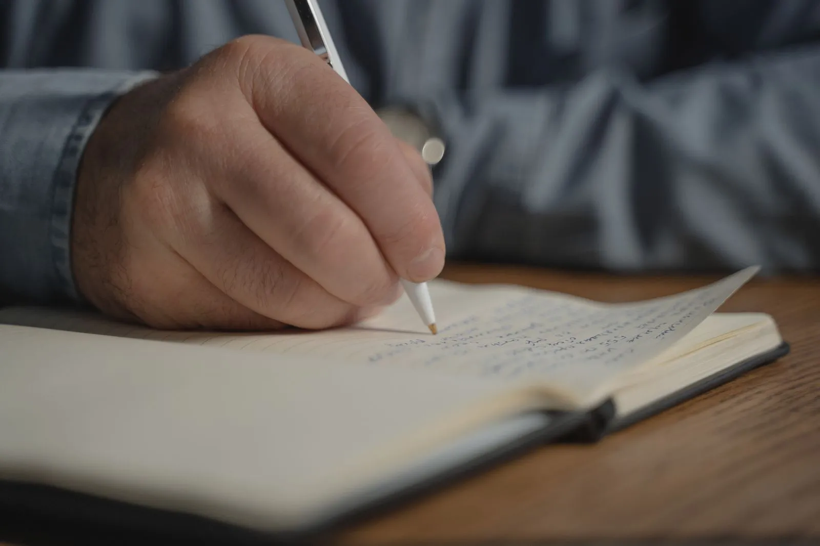 A hand writing notes in an open notebook